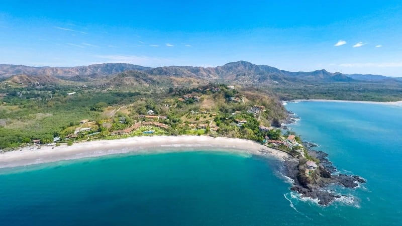 The small strip of land of Playa Flamingo jutting into the blue water in Costa Rica.