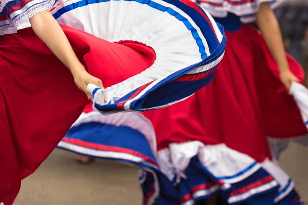 Two red, blue, and white traditional skirts are twirled during a dance.