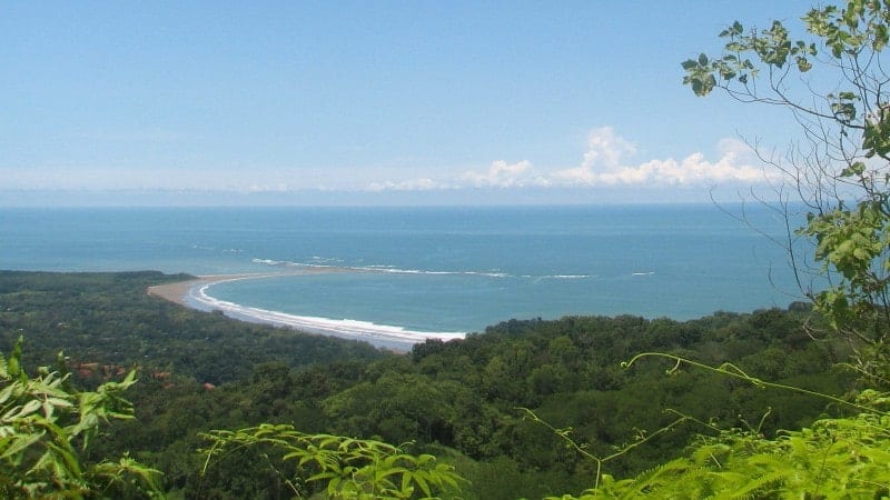 A beautiful bay in Costa Rica with a blue ocean and greenery surrounding the bay.