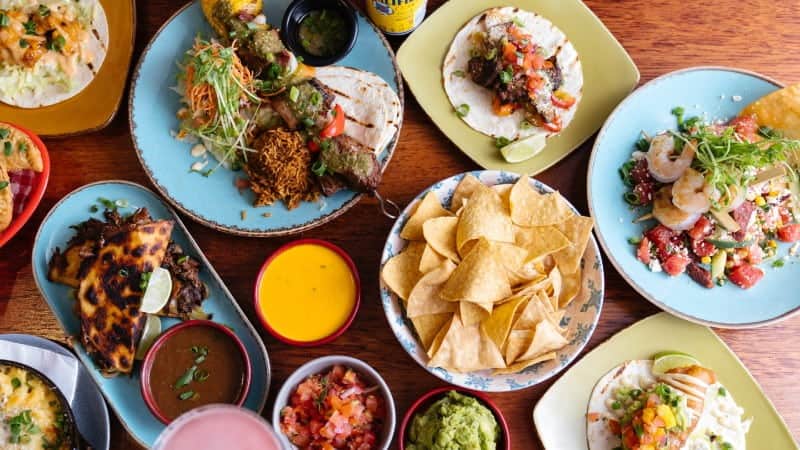A spread of Mexican food, including tacos, chips and salsa, guacamole, and more.