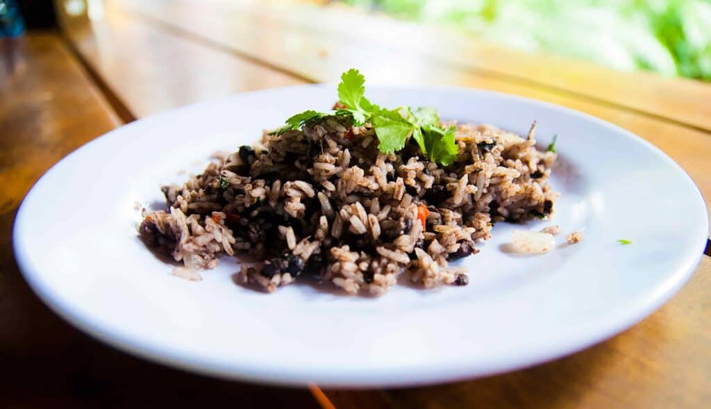 Gallo pinto, a rice and beans dish that is popular in Costa Rica, sitting on a plate on a wooden table.