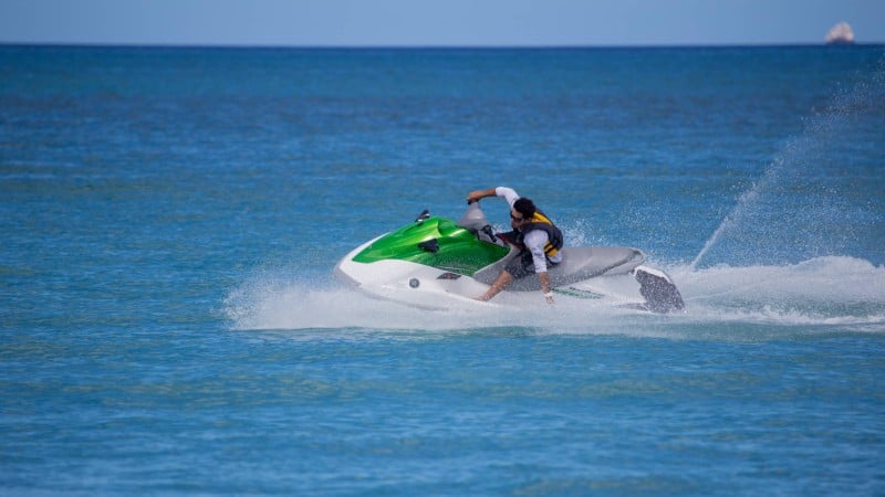 A man riding a lime green wave runner across the ocean in Costa Rica.