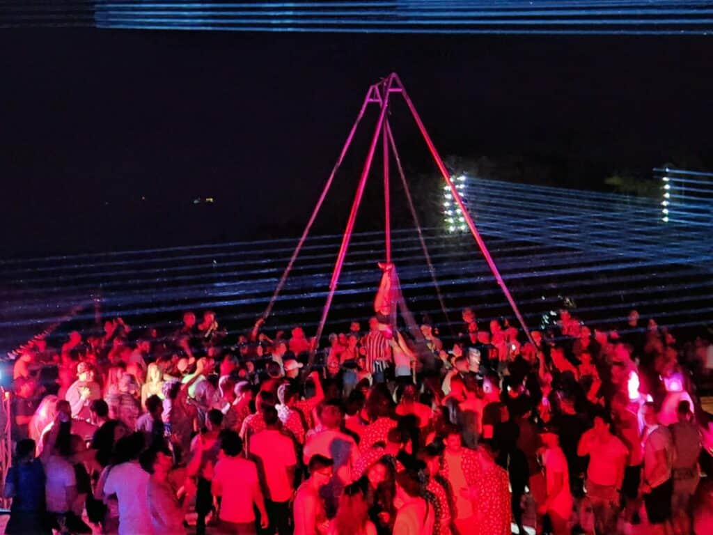 A large group of people gathered together in a nightclub with red lighting.