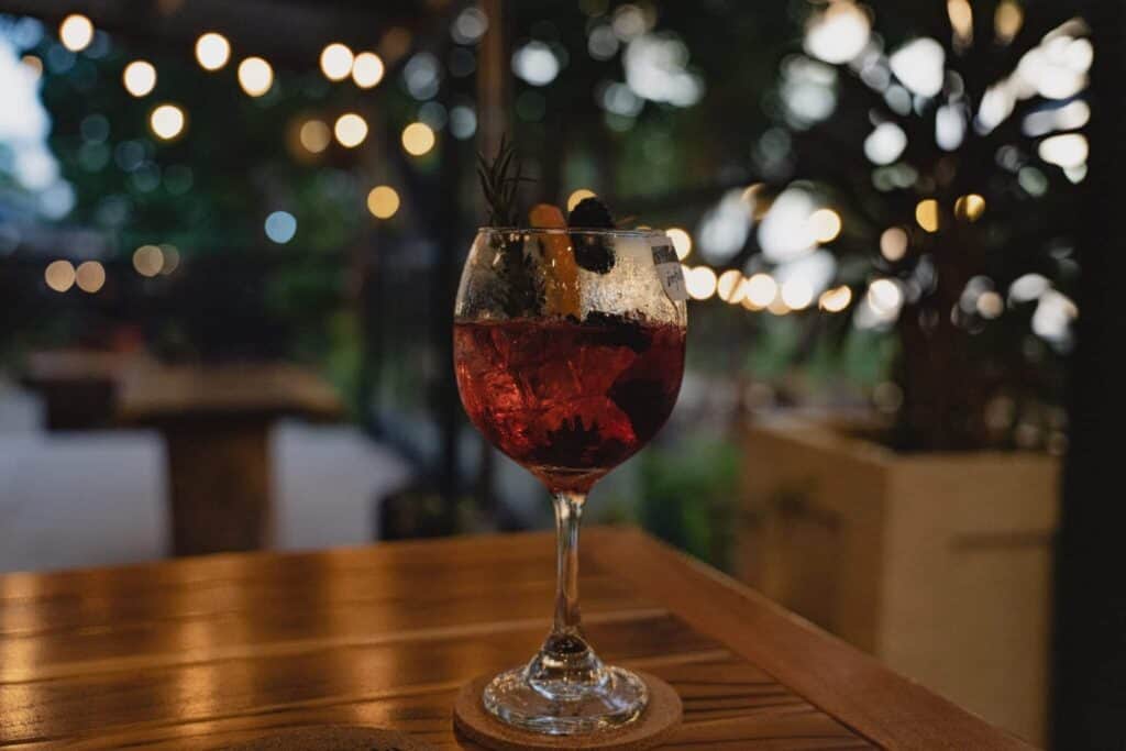 A glass of sangria sitting on a wooden table in Playa Tamarindo.
