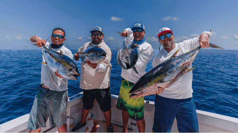 Four men holding four fish on a boat in the middle of the ocean in Costa Rica.
