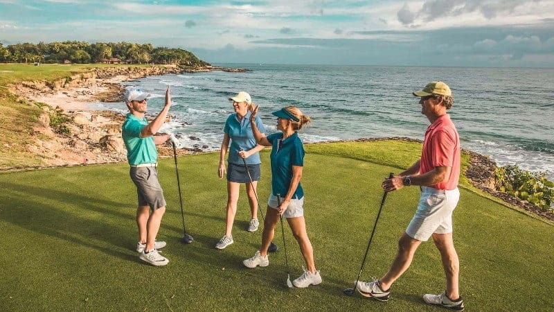 Two couples high-five after teeing off at the Reserva Conchal golf course