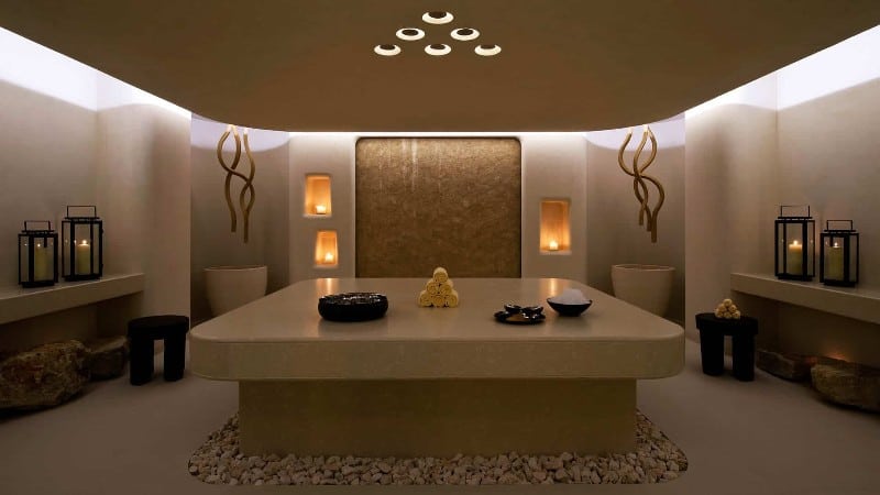 The tranquil entrance to the spa at Reserva Conchal, Costa Rica features soft lighting, large stone features with candles and interesting artwork.
