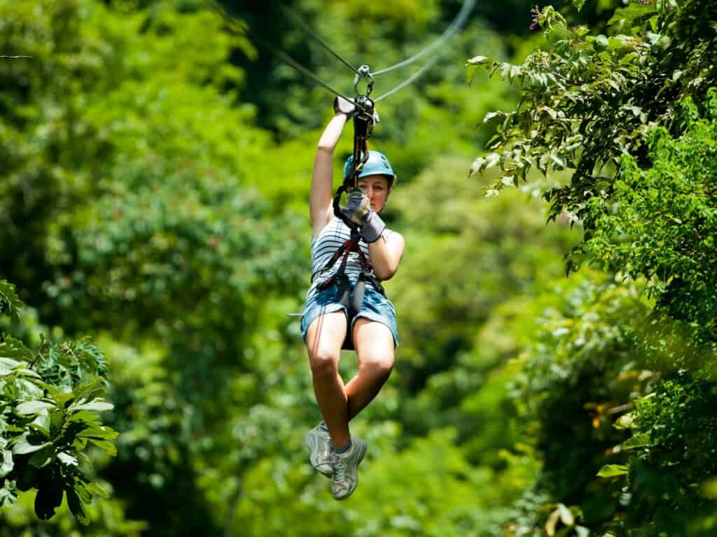 a girl sliding down a zipline at high speed in the rainforest in Costa Rica