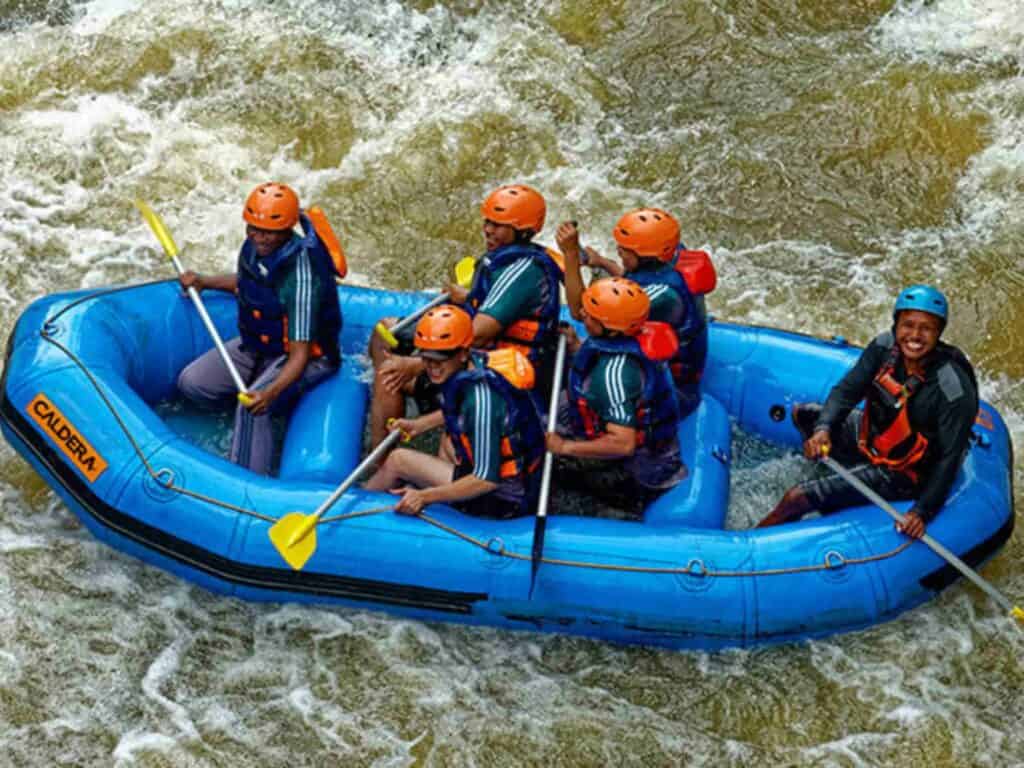 a group of people in a blue raft holding yellow oars while whitewater rafting in the Colorado River in Costa Rica