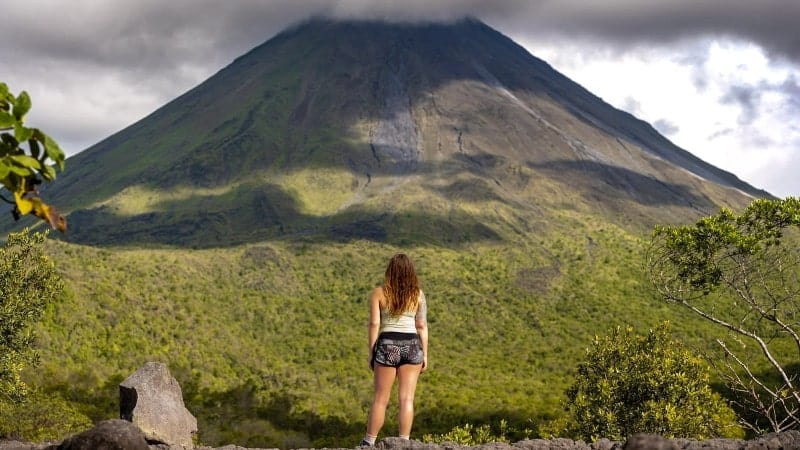 A woman standing in front of a beautiful volcano in Costa Rica.