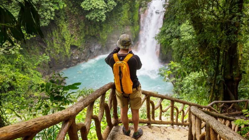 A man looking at a waterfall in the jungle in Costa Rica.