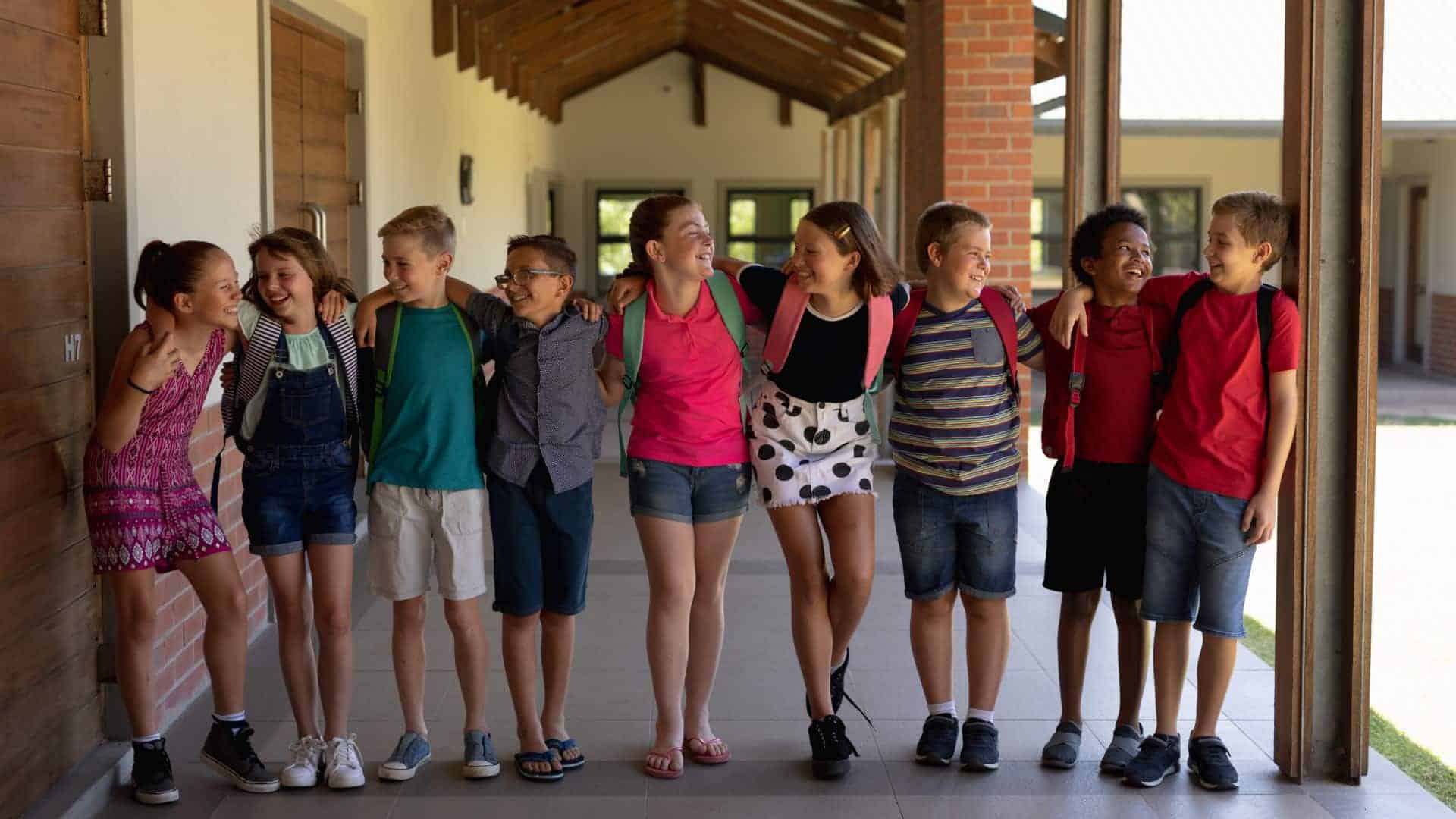 School children standing in a line putting their arms around each other's shoulders